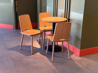 Wooden chairs and round table in a cafe. Minimalism, modern lifestyle, and urban dining atmosphere.
