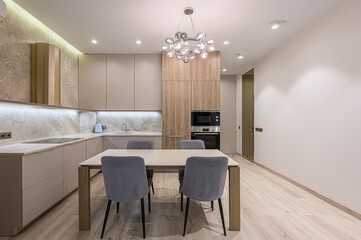 modern kitchen featuring light-colored cabinets, a dining table with four chairs, and a unique bubble chandelier. The space is well-lit and has a clean, minimalist aesthetic