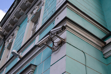 Obraz premium Surveillance cameras mounted on building corner, symbolizing urban security, safety technology, and public monitoring in smart cities. Reflecting modern security measures in urban spaces