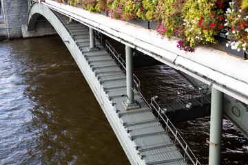 Close up view of arched bridge structure with strong metallic frame, highlighting engineering and architectural beauty of bridge design, complemented by greenery along its top