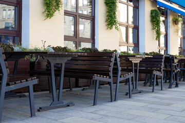Modern outdoor seating arrangement with benches and tables, accented by decorative planters. The minimalist design creates an inviting space for social gatherings in urban environments