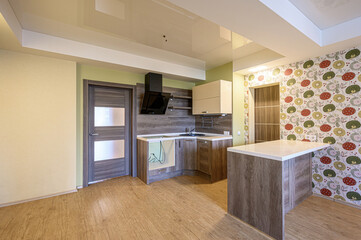 modern kitchen interior featuring wood-look flooring, cabinets, and a contrasting floral wallpaper. A black vent hood adds a sleek touch