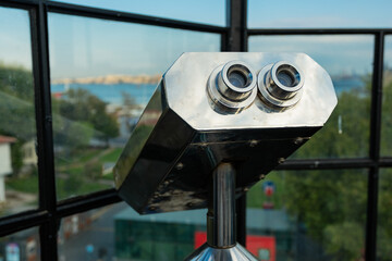 Tourist binoculars overlooking the cityscape. Travel, exploration, and urban sightseeing experience.