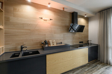 Modern kitchen with wood-look tile backsplash, black countertops, and black/wood cabinetry. Sleek, contemporary design