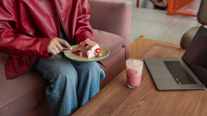Person enjoying cake and a pink drink at a cafe