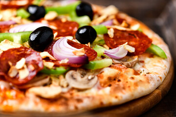 Pizza with chorizo ​​sausage, mozzarella cheese, green pepper and black olives. Rustic wooden background. Soft focus.	