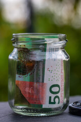Swiss franc CHF banknote saving money in glass jar. Consumption and economy