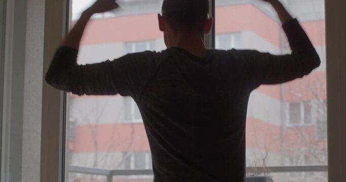 A person displaying dynamic movements and expressions indoors, showcasing energy and emotion with natural light streaming through the window.
