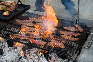 Closeup of Korean style beef cooking on an outdoor barbeque grill with hot coals below, dripping...