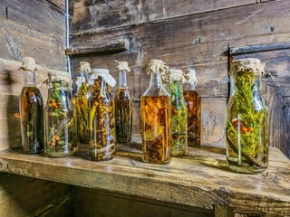 ​A collection of traditional herbal liqueurs, infusions, and tinctures in rustic glass bottles....