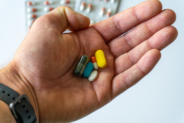person holds colorful tablets and capsules in hand: spirulina, turmeric, magnesium, and vitamins, commonly used as dietary supplements supporting overall health