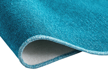 Close-up of a teal area rug, showing folded edge and fabric texture