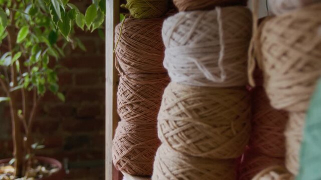 Close up detail shot of balls of yarn in muted brown colors stacked on wooden shelf in creative crafting workshop, copy space