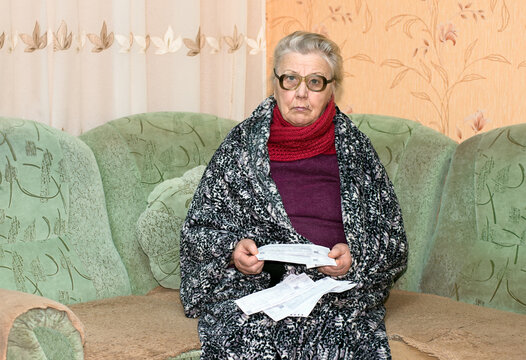 An elderly woman looks at utility bills.