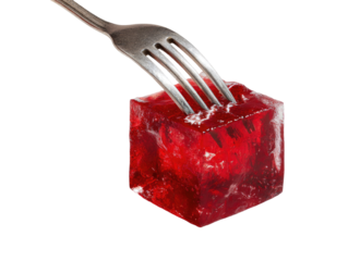 A metallic fork lifts a vibrant red, cubed gelatin dessert