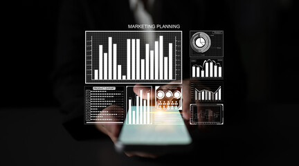 A business professional holds a smartphone displaying dynamic marketing planning data visualization. This image captures the essence of modern marketing strategy and analytics. Impute