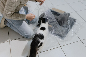 One person is assembling a new cat house at home with his cat.