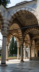 An intricate arcade structure with ornate striped arches and detailed ceiling patterns, bathed in soft sunlight.