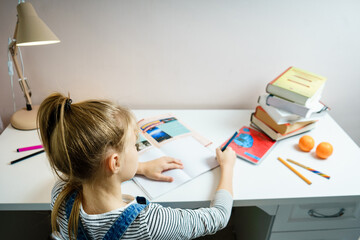 Teenage girl doing homework at table at home preparing for school test