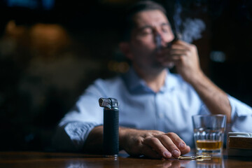 portrait of hansome man smoking cigar in a lounge bar