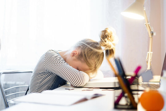 Relaxing. Pretty little girl sleeping over her books while sitting at the table and doing homework