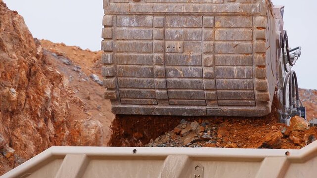 Excavator loads copper ore into big dump truck in open gold pit mine. Process gold mining industry workplace.