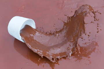 Spilled cocoa from a white mug onto a brown floor — a puddle of hot chocolate, a rich, velvety chocolate drink.