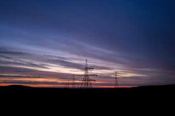 Electricity Pylons at Dawn Amid Vibrant Horizon in Rural Landscape