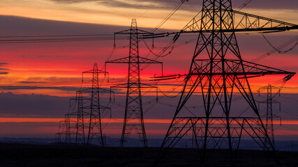 Electricity Transmission Towers at Sunrise Over Remote Countryside Landscape in England