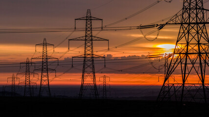 High Voltage Power Lines at Sunset with Scenic Orange Sky