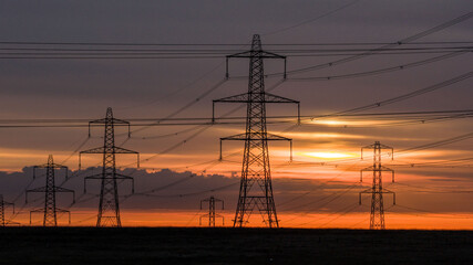 High Voltage Power Lines Against a Vibrant Sunrise Sky