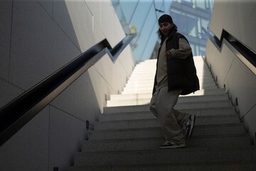 A man is currently walking down a long set of stairs, descending carefully as he makes his way to...