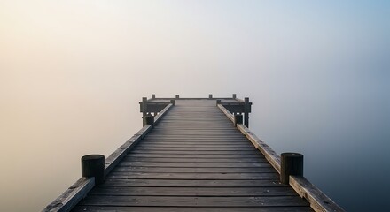 Fototapeta premium Wooden pier stretching into a misty, calm lake at sunrise, evoking peace and solitude.