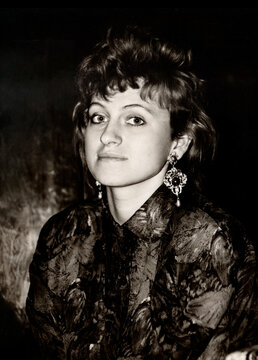 Vintage half-turned portrait of an extravagant beautiful young girl, dressed in the fashion of the 80s. Retro photo from 1987.