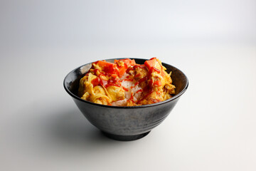 Omelette with carrot on steamed rice in black bowl, Asian homemade meal, traditional Thai comfort food isolated on white background