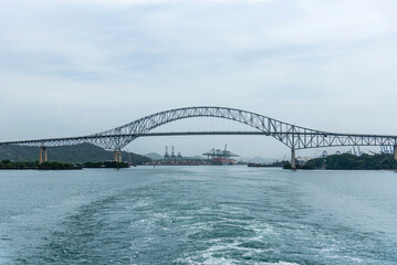 Bridge of Americas in Panama spans over a waterway, viewed from a transiting cargo ship. 