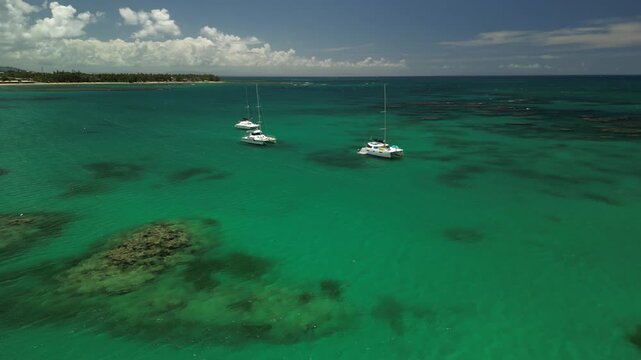 Aerial drone footage of catamarans anchored near Playa Punta Popy, with turquoise waters and palm beach