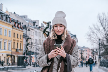 Winter city wanderlust: female tourist walking historic Warsaw old town, pastel facades and holiday...