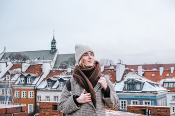 Winter city wanderlust: female tourist walking historic Warsaw old town, pastel facades and holiday...