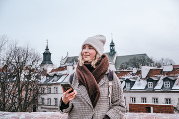 Winter city wanderlust: female tourist walking historic Warsaw old town, pastel facades and holiday...