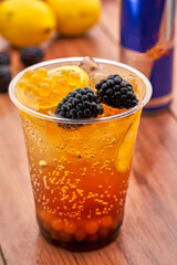 Refreshing Blackberry Mojito Cocktail with lime slices, and crushed ice in plastic cup closeup side view of summer drink