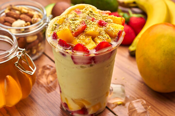 Vibrant Mango and Strawberry Smoothie or milkshake with Honey, Nuts, and Fresh Fruit in plastic cup...