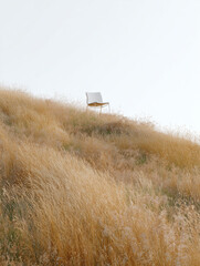 An image of a white chair against the blue sky in the steppe, in the wind, a conceptual illustration.