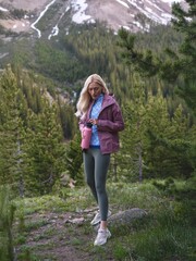 Naklejka premium Blonde Athletic Woman Admiring Mountain Views on Autumn Evening Hike in Forest Path