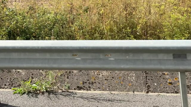 View of a guardrail on the side of a highway from a moving car