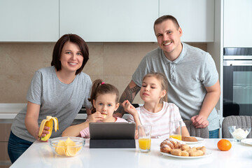 Smiling Family Dining Together at kitchen table and having fun, parents with two daughters