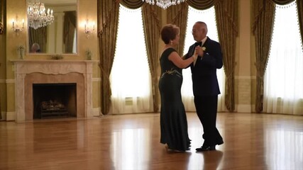 A Hispanic senior couple enjoys a romantic moment dancing in an opulent ballroom. The atmosphere is filled with elegance, highlighted by stunning chandeliers and soft lighting - Powered by Adobe