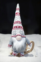 Christmas gnome in a hat with an ornament on a wooden sleigh close-up
