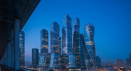 Obraz premium Urban Panorama: Modern Skyscrapers Illuminate the Evening Skyline with Vibrant Lights