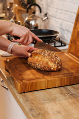 Slicing multigrain bread on a wooden board in a cozy home kitchen environment